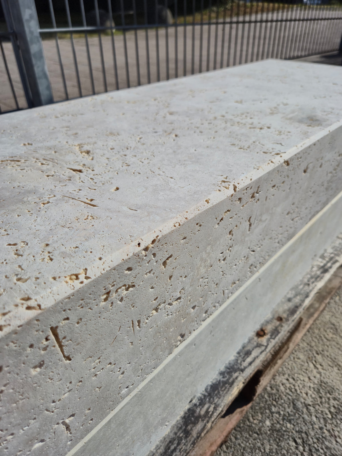 Seitliche Nahaufnahme einer Blockstufe aus Travertin Classic Beige mit Porenstruktur und gerader Längskante.